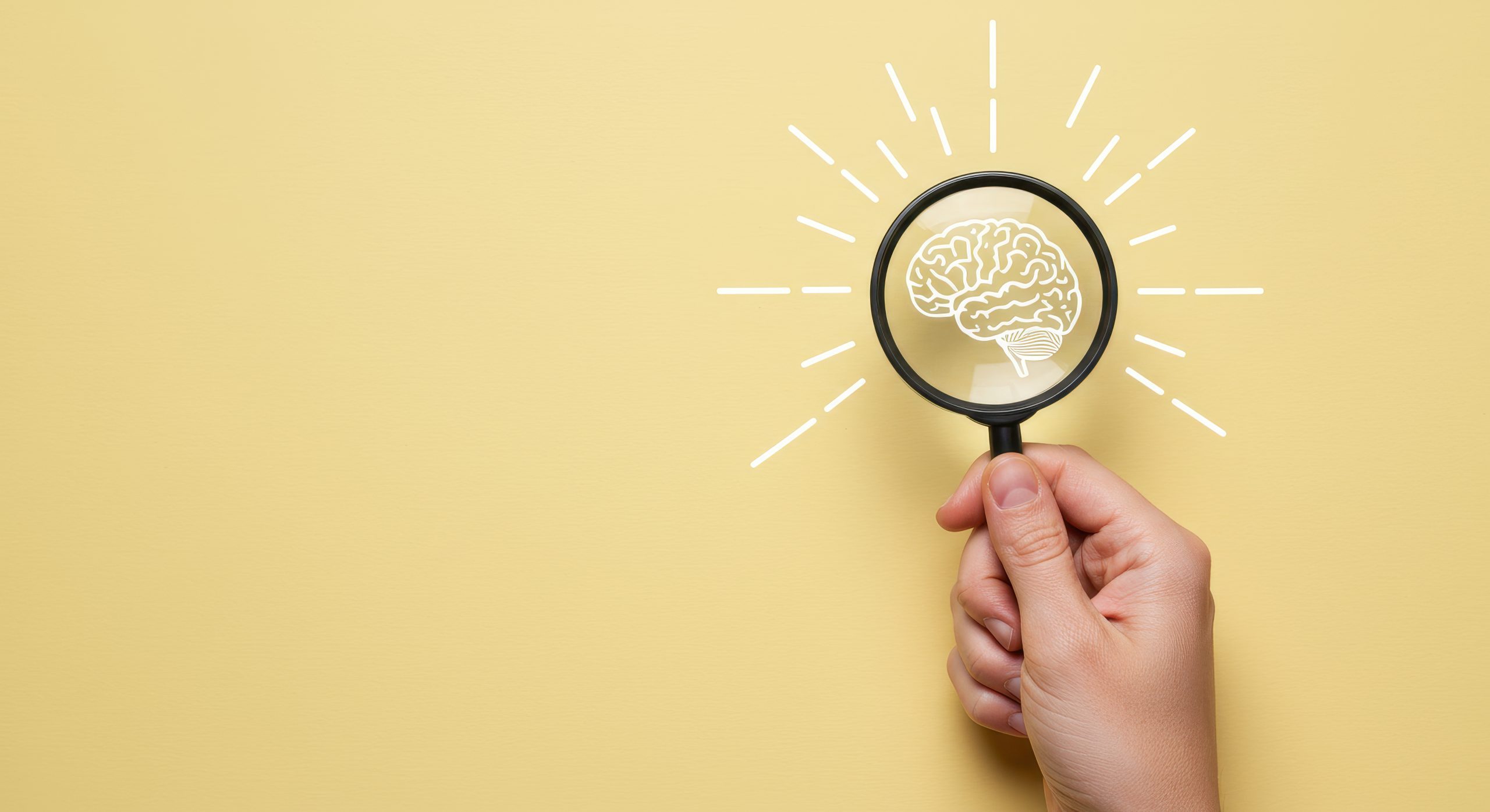Lente di ingrandimento su sfondo giallo che inquadra il disegno di un cervello stilizzato