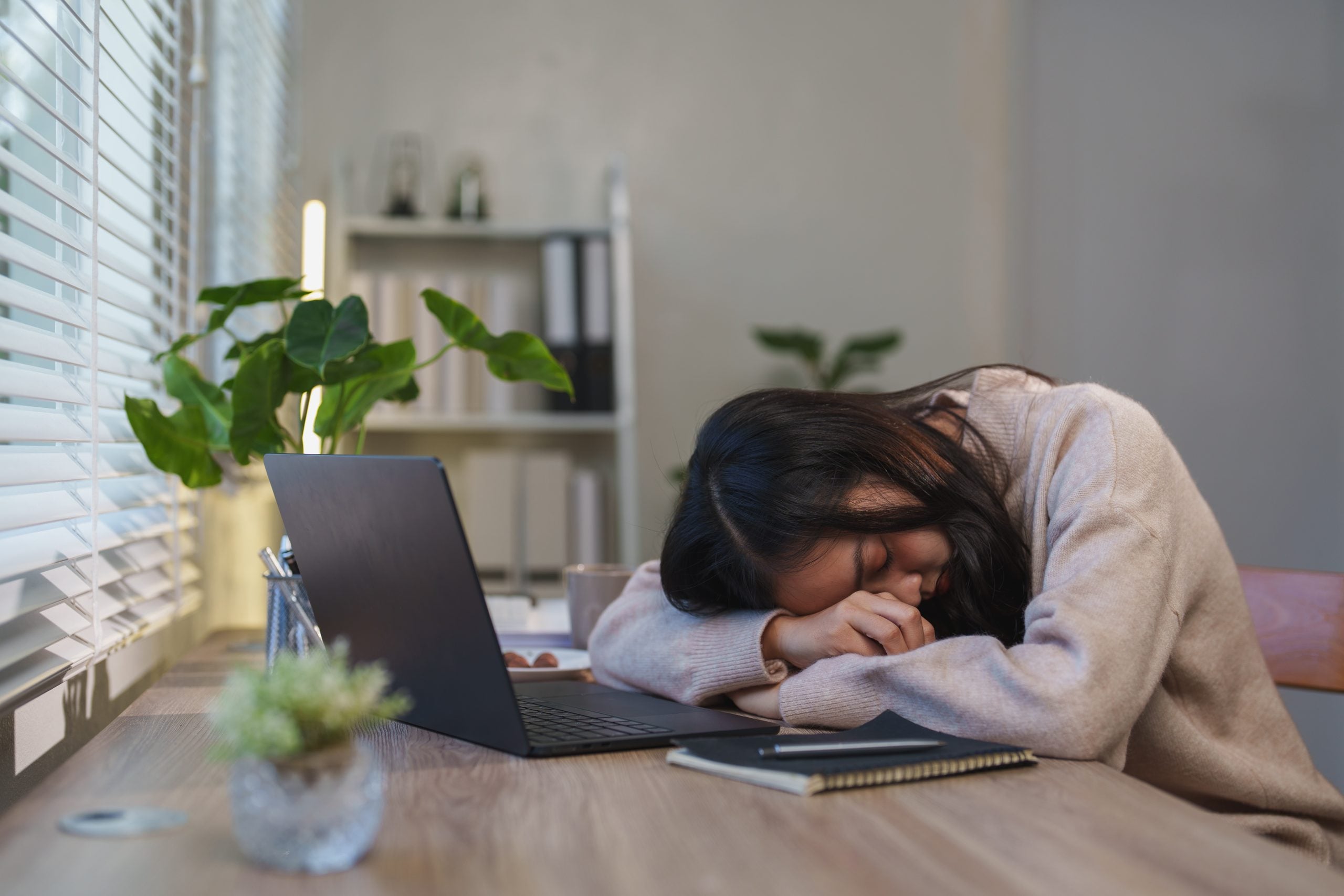 Ragazza sdraiata con il viso sul tavolo e il pc davanti a sé per la stanchezza da smarworking