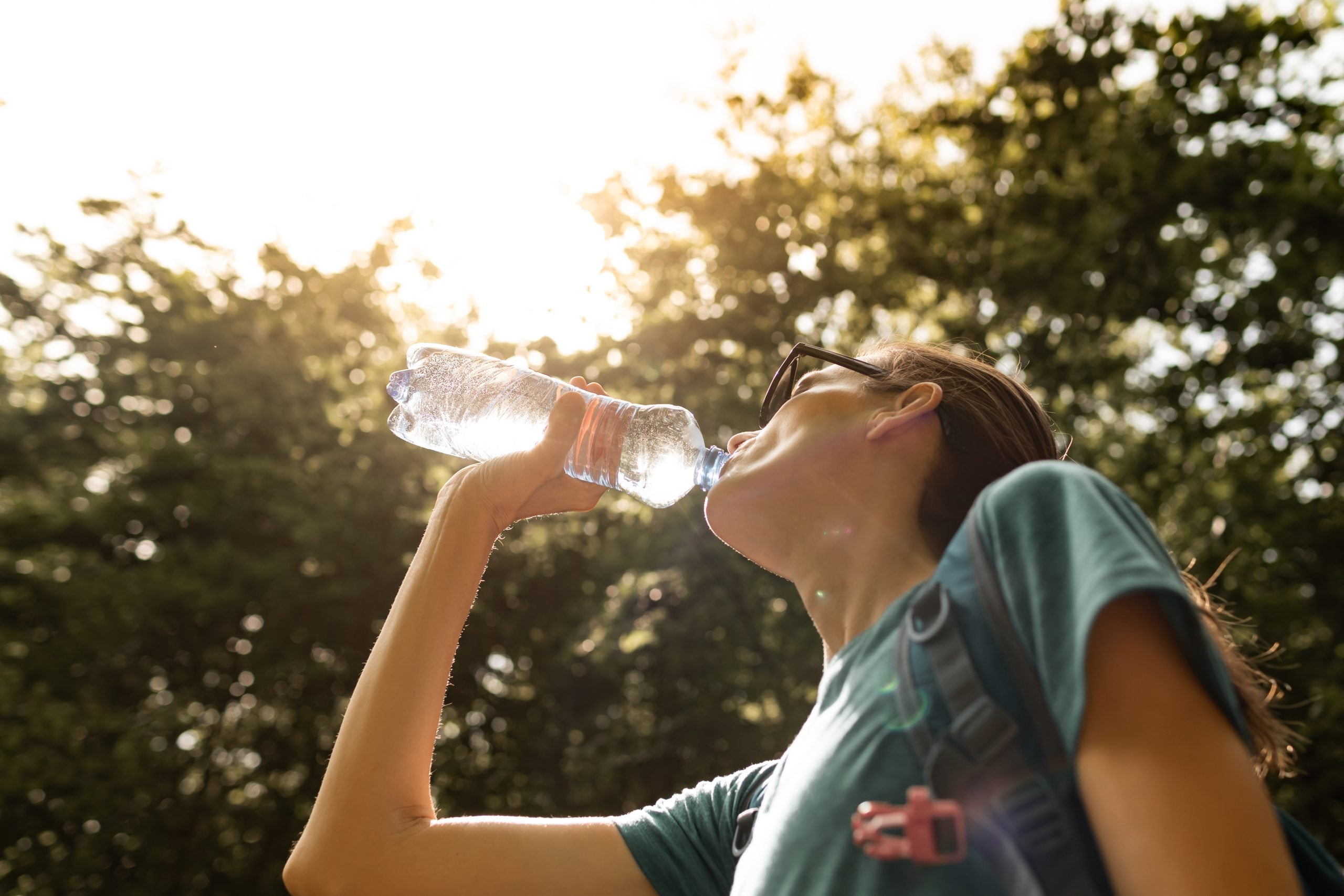Ragazza che beve da una bottiglia d'acqua per combattere la disidratazione
